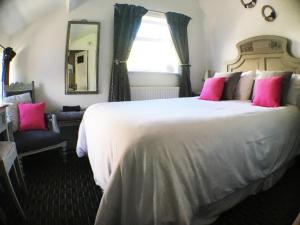 a bedroom with a large white bed with pink pillows at Hillside Bed and Breakfast in Crediton