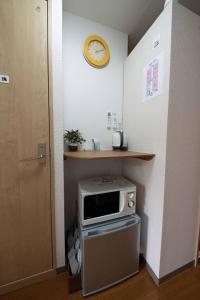 a kitchen with a microwave and a clock on the wall at Taro's Hostel Minami Koshigaya in Koshigaya