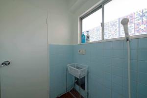 越谷市にあるタローズホステル南越谷の青いタイル張りのバスルーム(窓、シャワー付) +17枚の写真