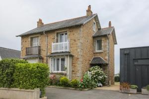 a brick house with a balcony and a black garage at Kerelen in Carantec