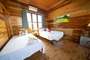 two beds in a room with wooden walls at Diep Le Homestay in Phong Nha