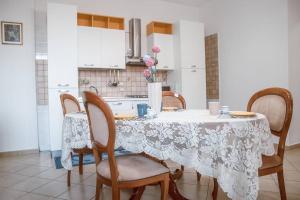 uma cozinha com uma mesa com cadeiras e uma toalha de mesa branca em Annabella's Country House historic apartment em SantʼAntonio Abate