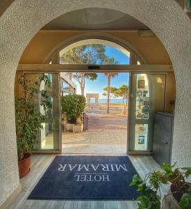 une porte ouverte avec un tapis de bienvenue devant un bâtiment dans l'établissement Hotel Restaurant Miramar L'orchidée, à La Ciotat