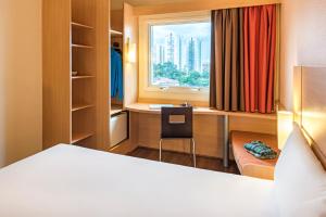 a bedroom with a bed and a desk and a window at ibis Sao Paulo Interlagos in Sao Paulo