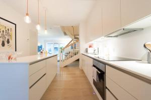 a kitchen with white cabinets and a wooden floor at 2Floors New Apartment & Charming Canal Surrounding in Copenhagen