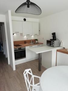 a kitchen with white cabinets and a table and chairs at Le Saint Amand, studio cabine, agréable terrasse sud in Le Touquet-Paris-Plage