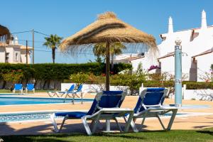 
a beach area with chairs, tables, and umbrellas at Moradias Villas Joinal in Albufeira

