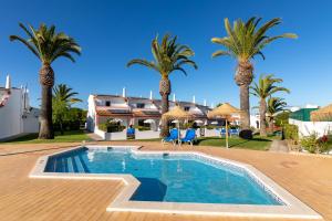 a villa with a swimming pool and palm trees at Moradias Villas Joinal in Albufeira