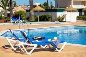 
a man sitting on a blue chair in front of a pool at Moradias Villas Joinal in Albufeira
