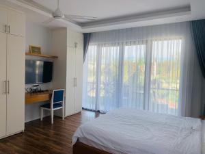 a bedroom with a bed and a desk and a television at Ocean Pearl Villa in Vung Tau