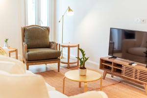 a living room with a television and a chair at Apartamentos Ferreiros by Heart of Funchal in Funchal