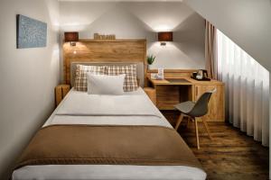 Schlafzimmer mit einem Bett, einem Schreibtisch und einem Stuhl in der Unterkunft Neo Hotel Linde Esslingen in Esslingen