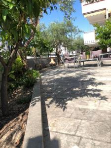 chodnik z dwoma ławkami i drzewami w parku w obiekcie Glykanisos Suites w mieście Néa Péramos
