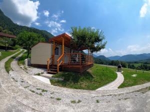 a small cabin with a tree on the side of a road at Holiday HOUSE NEAR THE SOČA RIVER in Tolmin