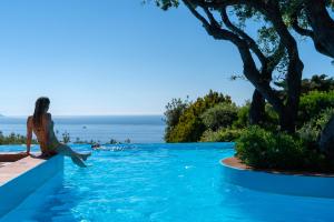 a woman sitting on the edge of a swimming pool at Boutique Hotel Torre Di Cala Piccola in Porto Santo Stefano