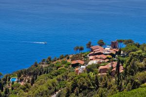 a house on a hill near the ocean with a boat at Boutique Hotel Torre Di Cala Piccola in Porto Santo Stefano