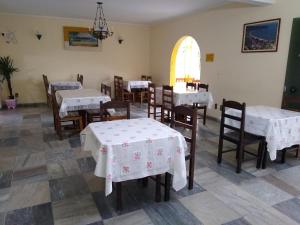 una sala da pranzo con tavoli, sedie e una finestra di Pousada da Costa a Caraguatatuba