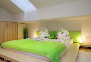 a bedroom with a large bed with green sheets and pillows at Chalet Der Bichlhof in Zell am See