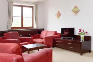a living room with red chairs and a tv at Hotel Tulipan in Tatranská Lomnica