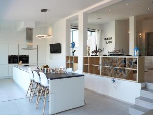 een keuken met een wit eiland met krukken bij Casa Lou, architect villa with heated pool at Begur, 470m2 in Begur