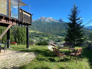 a house with two chairs and a table and a tree at soleil et vue in Barcelonnette