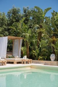 een zwembad met een tafel en een bank naast enkele bomen bij Residenza Il Sole in Monopoli