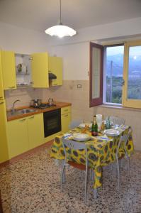une cuisine avec une table, des chaises et des armoires jaunes dans l'établissement Gole dell'Alcantara Villa Lucia II, à Motta Camastra