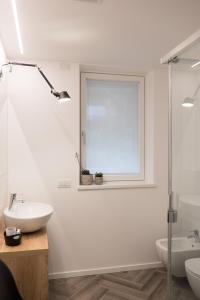 ein weißes Bad mit einem Waschbecken und einem Fenster in der Unterkunft Terrazze dei Tigli in Riva del Garda
