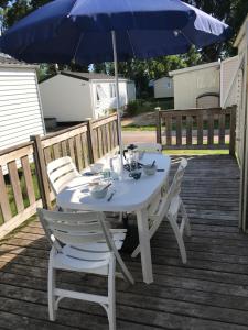 a table and chairs with an umbrella on a deck at Mobil Home à Meschers au camping l'Escale proche de Royan in Meschers-sur-Gironde