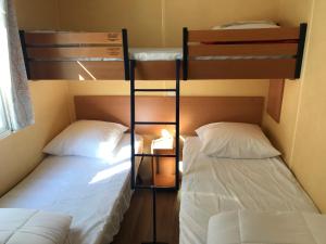two bunk beds in a small room with two white beds at Mobil Home à Meschers au camping l'Escale proche de Royan in Meschers-sur-Gironde +9 photos