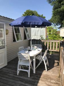 a table and chairs under an umbrella on a deck at Mobil Home à Meschers au camping l'Escale proche de Royan in Meschers-sur-Gironde