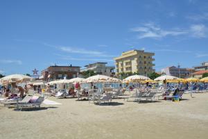 una playa con sillas y sombrillas y gente en ella en Hotel Palos, en Rímini