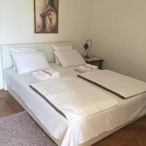 a bed with white sheets and pillows in a room at Maja Apartment in Lovran