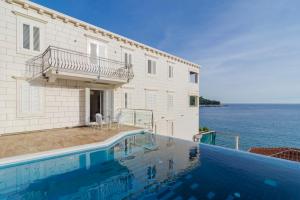 a house with a swimming pool next to the water at Pine Tree Boutique Apartments in Saplunara