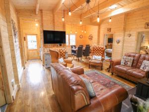 Bryn Derwen Lodge في بانغور: غرفة معيشة مع أثاث من الجلد وغرفة طعام