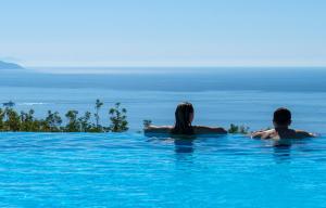 a man and woman sitting in the water in a swimming pool at Boutique Hotel Torre Di Cala Piccola in Porto Santo Stefano