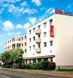 Un grand bâtiment blanc avec un panneau sur son côté dans l'établissement ibis Strasbourg Aéroport Le Zénith, à Lingolsheim