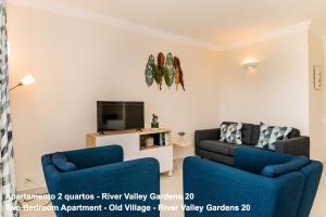 a living room with two blue chairs and a tv at Akisol Vilamoura Villag in Vilamoura