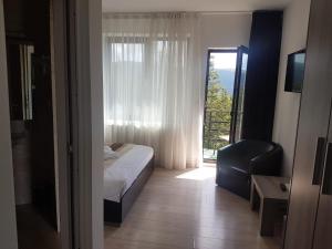 a bedroom with a bed and a chair and a window at Vila Ozon in Ranca
