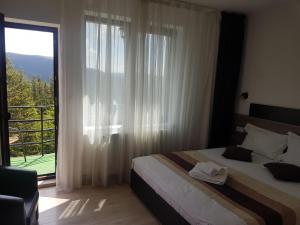 a bedroom with a bed and a large window at Vila Ozon in Ranca