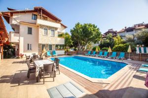a swimming pool with chairs and a table next to a house at Villa Gardenia in Dalyan