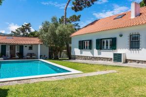 a villa with a swimming pool in front of a house at Sintra • Banzão House with Swimming Pool in Nafarros