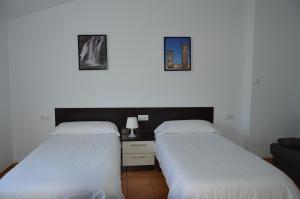 two beds in a room with two pictures on the wall at Rural Reillo Alojamientos Rurales in Reíllo