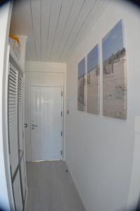 a hallway with three paintings on the wall and a door at Joli studio rénové Emplacement idéal front de mer in Cabanas de Tavira