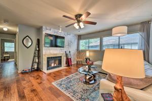 a living room with a ceiling fan and a fireplace at Cozy Woodlands Townhome with Deck Near Market Street in The Woodlands