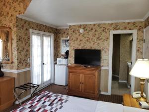 a bedroom with a television and a kitchen with a refrigerator at Gazebo Inn in Branson