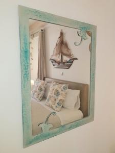 a mirror hanging on a wall with a bed with a sail at Helens Apartment in Corfu Town
