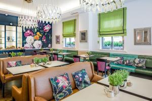 un restaurante con mesas, sillas y cortinas verdes en Hotel Goliath am Dom en Regensburg