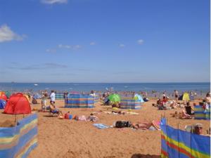 a crowd of people on a beach with umbrellas at Coombe Lodge Holiday Flats in Paignton
