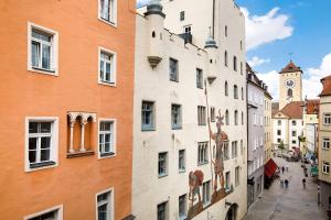 una calle de la ciudad con edificios y una torre del reloj en Hotel Goliath am Dom, en Regensburg